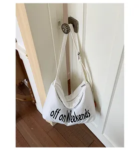 Large white nylon shoulder bag with 'off on Weekends' print hanging on a door handle.