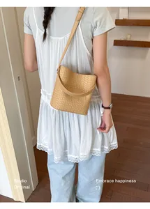 Close-up detail of a minimalist tan woven bucket bag with elegant shoulder strap