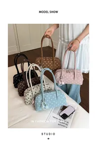 Verschillende kleuren polka dot schoudertassen vastgehouden door een modieus model