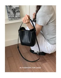 Close-up of the elegant black woven bucket bag being held by a model in a studio