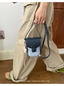 Vintage blue saddle crossbody bag shown in a stylish street-style fashion setting.
