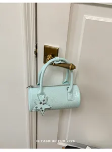 Detail of light blue woven cylinder handbag with a star charm hanging on a door handle.