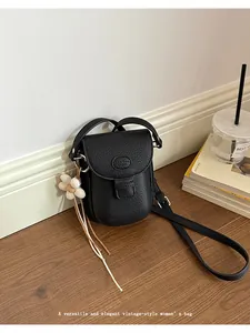 Detailed view of a vintage black leather saddle bag with flower charm on a floor.