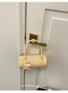Small cream woven barrel handbag hanging on a vintage brass door handle