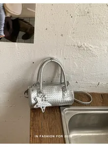 Detail view of a metallic silver woven barrel bag with star charm detail