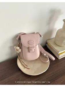Macro view of a vintage pink grained leather crossbody bag featuring a flower charm accessory