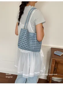 Model wearing a white dress and carrying a light blue hollowed-out woven tote bag