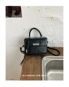 Dettaglio di una borsa a tracolla vintage in pelle nera su piano in legno rustico