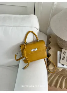 Elegante borsa quadrata gialla vintage con chiusura a scatto argento su divano bianco.