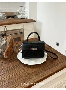 Primo piano di una borsa a mano vintage in pelle nera su un tavolo di legno rustico.