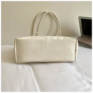 Vue détaillée de la couture du fond d'un grand sac cabas minimaliste blanc cassé