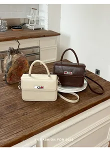 Borse a mano vintage quadrate in pelle crema e marrone su un tavolo di legno