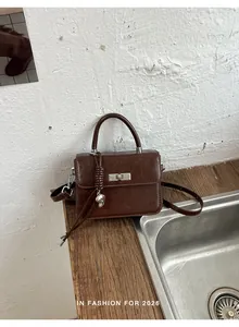 Dettaglio di una borsa vintage in pelle marrone con manico e serratura argento