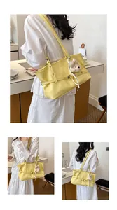 Vue détaillée d'un chic sac fourre-tout jaune sous le bras avec un charmant peluche