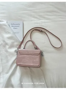 Vista posteriore di una borsa a tracolla quadrata rosa antico con manico e texture