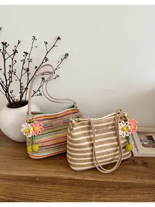 Detailopname van bohemien geweven strooien schoudertassen met strepen en bloemhangers