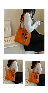 Lifestyle shot of a woman carrying a vibrant orange nylon shoulder bag with rabbit charm.
