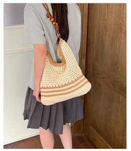 Bohemian hand-woven straw tote bag with unique wooden bead strap shown on a model