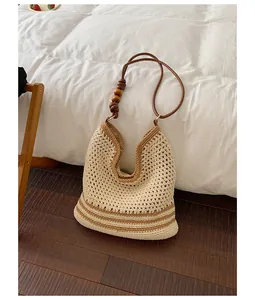 Handmade woven straw tote bag featuring brown shoulder strap and wooden bead details