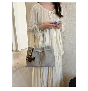 Grey woven tote bag with dachshund charm worn by model in a minimalist setting