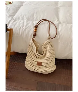 Detail view of handmade woven straw bag with leather strap and wooden beads decoration