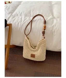 Hand-woven cream crochet shoulder bag with wooden bead strap and leather patch detail