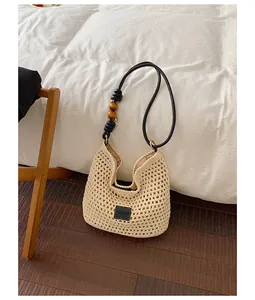 Large handmade woven straw shoulder bag with wooden beads decoration for beach vacation.
