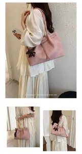 Detailed view of large pink textured tote bag with horse charm on an Asian model.