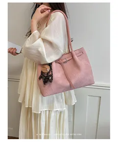 Macro view of a large pink tote bag with textured finish, worn by a model in a dress.
