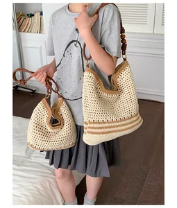 Detailed view of hand-woven straw tote bags with brown striped accents and bead straps.