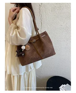 Brown textured commuter tote bag carried by a model against a minimalist wall.