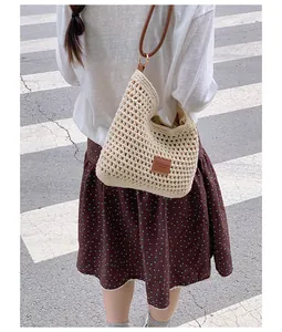 Detailed view of a handmade woven straw tote bag worn over the shoulder outdoors.