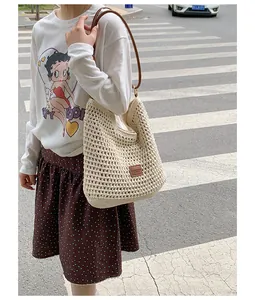 Detailed view of the large hand-woven straw shoulder bag in a street setting
