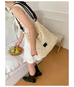 Close-up detail of large capacity handmade woven straw tote bag with stylish wooden beaded strap