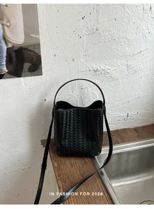 Close-up detail of a premium black woven bucket bag with leather texture and strap