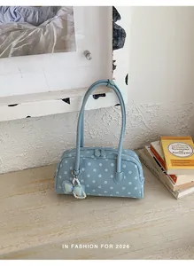Lichtblauwe handtas met polkadots en parel-strik hanger in een lifestyle setting