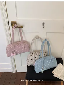 Detailopname van drie stijlvolle schoudertassen met polkadots in roze, beige en blauw.