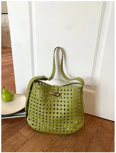 Detail van groene geweven opengewerkte draagtas met elegante hoornen knoopsluiting