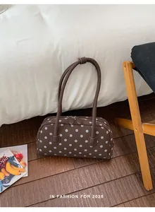 Lifestyle-weergave van een bruine schoudertas met polkadots op een houten slaapkamervloer