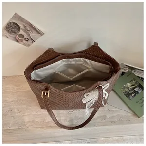 Vue détaillée de l'intérieur d'un grand sac cabas tressé marron avec de multiples poches