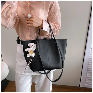 Elegant black leather tote bag with decorative horse charm held by model for daily commute