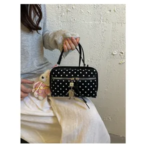 Detailed view of a stylish black polka dot handbag for women with a cute robot charm