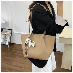 Side view of a khaki large capacity commuter tote bag with a white horse charm