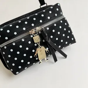 Detailed shot of a black polka dot handbag featuring a unique metal robot zipper charm.