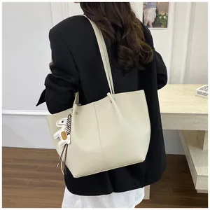 Large beige pebbled leather tote bag shown on a shoulder in a modern room setting