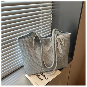 Détail d'un sac cabas tissé bleu clair orné d'un élégant nœud en dentelle et perles