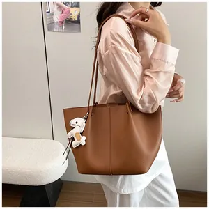 Detailed view of an elegant brown leather tote bag carried by a woman in a stylish outfit
