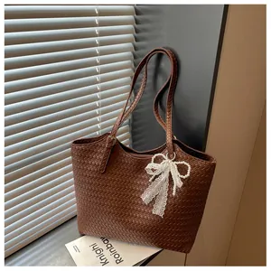 Vue détaillée du sac cabas marron en cuir tressé avec nœud en dentelle et perles