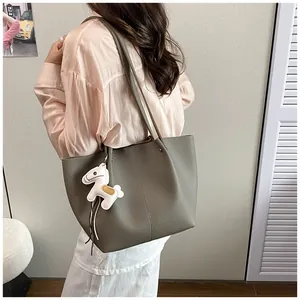 Premium grey commute tote bag with cute horse charm detail shown on model shoulder.