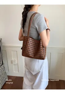 Brown woven hollow tote bag carried by a model in a stylish indoor setting macro view